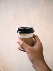 Hand holding a cup of coffee in disposable or take away packaging