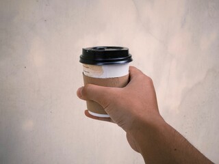 Hand holding a cup of coffee in disposable or take away packaging