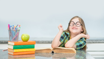 Funny little girl wearing eyeglasses doing homework at home