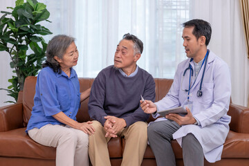 Obraz premium health care worker in uniform with stethoscope,holding tablet computer,taking mercury measurement and giving advice elderly couple at home,home health services,home care