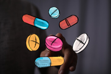 Hand interacting with colorful pills and capsules.  Healthcare, medicine, pharmacy concept.