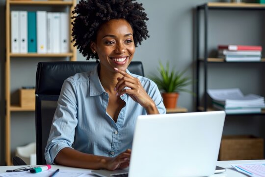 An African American female tax professional working diligently at her desk with colorful invoices and digital e-invoices visible on her laptop screen.