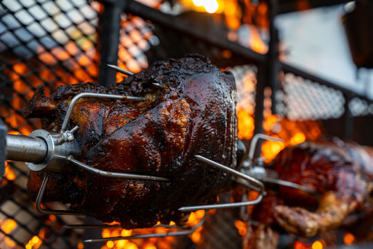 Vue d&rsquo;un cochon entier cuit &agrave; la broche lors d&rsquo;une pr&eacute;paration traditionnelle, illustrant une cuisson lente en ext&eacute;rieur avec une pr&eacute;sentation conviviale.