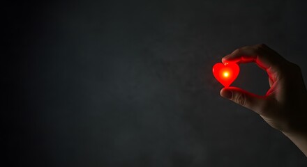 Hand Holding a Small Glowing Red Heart in a Dark Room