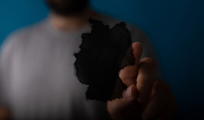 Abstract image of a man holding a black shape resembling a map.  Perfect for concepts of loss,...