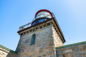 Historic Point Sur Lighthouse, Big Sur, California, USA. Stone tower with red lantern room against a clear blue sky, iconic landmark along Pacific Coast Highway 1 with rich maritime heritage