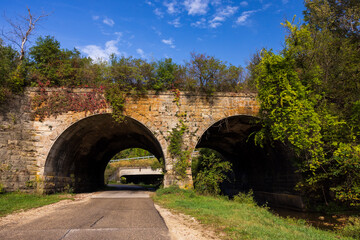 Fototapeta premium A Double Arch Stone Bridge With Road and Creek