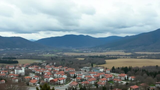 Town Plovdiv with houses and fields against backdrop of Rhodope Mountains and hills covered with forests and cloudy sky
