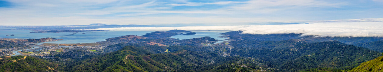 Panoramic view from Mount Tamalpais East Peak overlooking San Francisco Bay, Richmond San Rafael Bridge, Angel Island, and rolling hills of Marin County under fog and blue sky, California USA