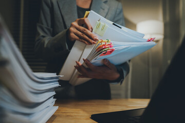 A person organizing a large stack of documents with binder clips on an office desk, representing...