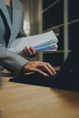 A person organizing a large stack of documents with binder clips on an office desk, representing paperwork, business management, and corporate workload.