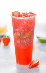 Refreshing strawberry drink in tall glass with ice and fresh fruit garnish