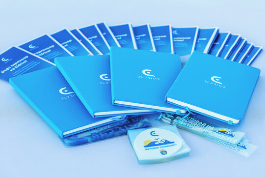 BURGAS, Bulgaria - September 20, 2025: Set of branded blue notebooks, brochures, merchandise with Eldrive logo on table. Concept of corporate identity, eco mobility branding, promotional materials