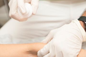 Fototapeta premium Close-up of a physiotherapist's hands expertly using an ultrasound transducer to treat a patient.