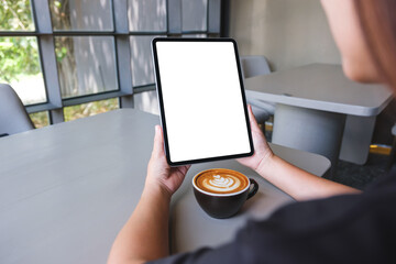 Mockup image of a woman holding digital tablet with blank white desktop screen in cafe