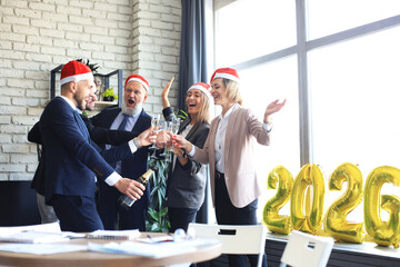 Business people are celebrating holiday in modern office drinking champagne and having fun in coworking. Merry Christmas and Happy New Year 2026.