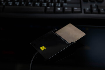 Smart card inserted into a USB card reader on dark background with keyboard. Concept of digital identity, online authentication, secure access, fintech, electronic ID, and cybersecurity system.