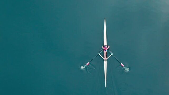 Rowing Top view of professional rower in racing boat, symbol of strength, determination and healthy active lifestyle. Single scull athlete training on water, in slow motion video 120fps.