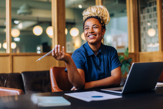 Smiling young woman holding pen while working in an office environment