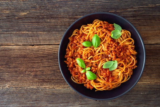 Spaghetti con rag&ugrave; alla bolognese - pasta with minced meat and tomato sauce on wooden table