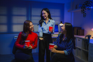 Asian business women colleagues socializing, sharing food and drinks at office party, having fun after work hours