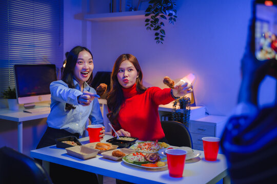 Happy young Asian women enjoying office dinner party, friends taking social media video, having fun