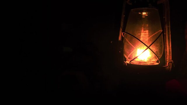 A calm, thoughtful Indian woman holds a glowing kerosene lantern in the warm darkness, her pensive expression evoking mystery, hope, and quiet strength as the soft light illuminates the night.