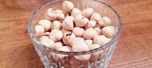 Raw hazelnuts without shells in a bowl on a white background