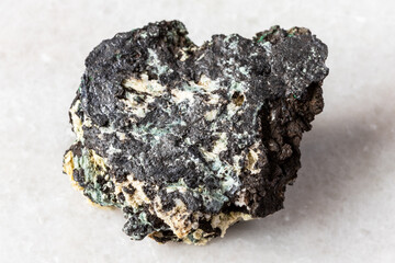 sample of raw tenorite mineral on white marble