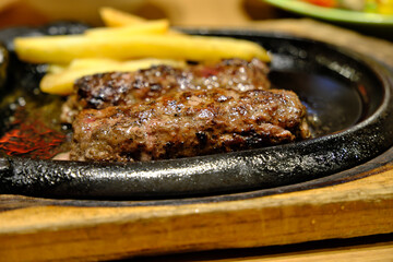A Juicy Hamburg Steak Sizzling on a Hot Cast-Iron Platter