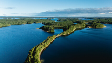 Fototapeta premium Punkaharju offers an enchanting view with its winding esker road surrounded by sparkling blue waters and lush green islands.