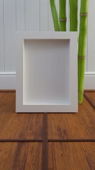 White Modern Frame with Zen Bamboo Background on Wooden Surface for Art Display