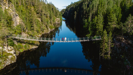 Two hikers stand on a stunning suspension bridge that crosses the tranquil waters of Canyon Lake in...