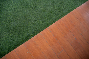 Diagonal composition of green artificial grass and brown wood deck flooring. Abstract background for landscape design or texture concepts