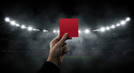 Hand holding up a red card in a stadium, symbolizing disqualification or penalty in a sporting event.