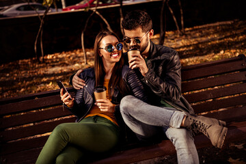 Young couple enjoying quality time on a bench amidst autumn foliage, sharing a moment of bonding, love, and leisure together