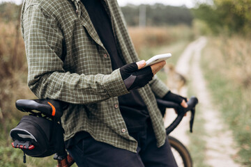 Man cyclist in casual clothes wearing gloves using smartphone.