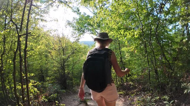 Hiker with backpack walking a forest trail in the Danube gorge, enjoying the sunlit nature and views over the Great Boilers area in Serbia and Romania. SLOW MOTION