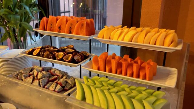 A buffet table is laden with fresh tropical fruits and breakfast items