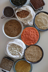 Bowls and bags full of various healthy grains and legumes. Top view.