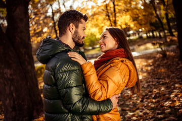 Fototapeta premium Young couple enjoying a romantic moment together in a scenic autumn park filled with colorful foliage