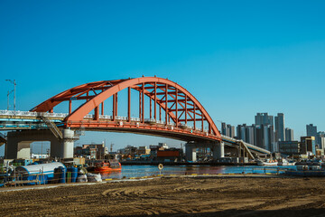 Obraz premium Red arch bridge over Sokcho harbor with city skyline, South Korea