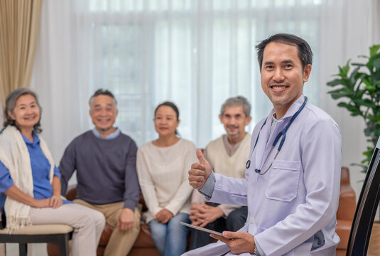 portrait a doctor or psychologist in uniform with stethoscope holding tablet computer,sitting in counselling room,background blurred elderly group therapy