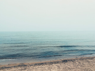 A quiet lakeshore scene with a sandy beach leading into calm, rippling water.