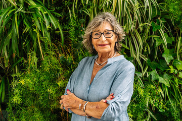 Senior woman smiling, confident, standing against green wall
