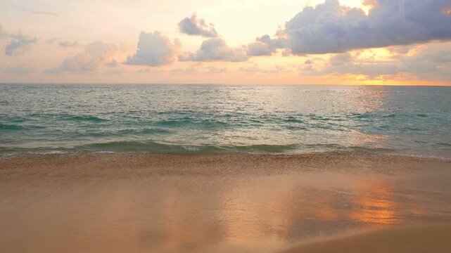 Golden sunset over the sea with gentle waves lapping on the sandy beach shore