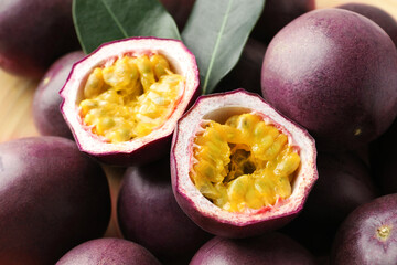 Fresh passion fruits with green leaves on table, closeup