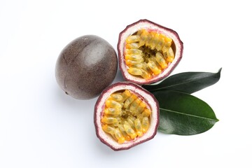 Fresh passion fruits with green leaves on white background, top view