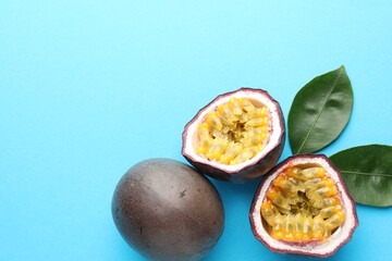 Fresh passion fruits with green leaves on light blue background, above view. Space for text