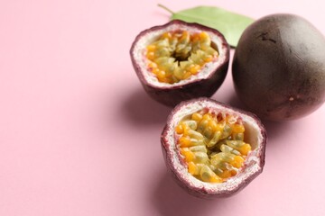 Fresh passion fruits and green leaf on pink background, closeup. Space for text